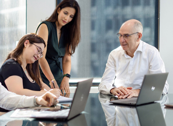 Pride team members having a discussion at a desk.