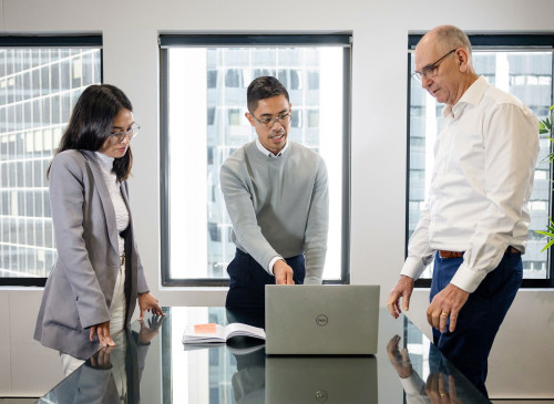 Pride team members having a discussion around a laptop.